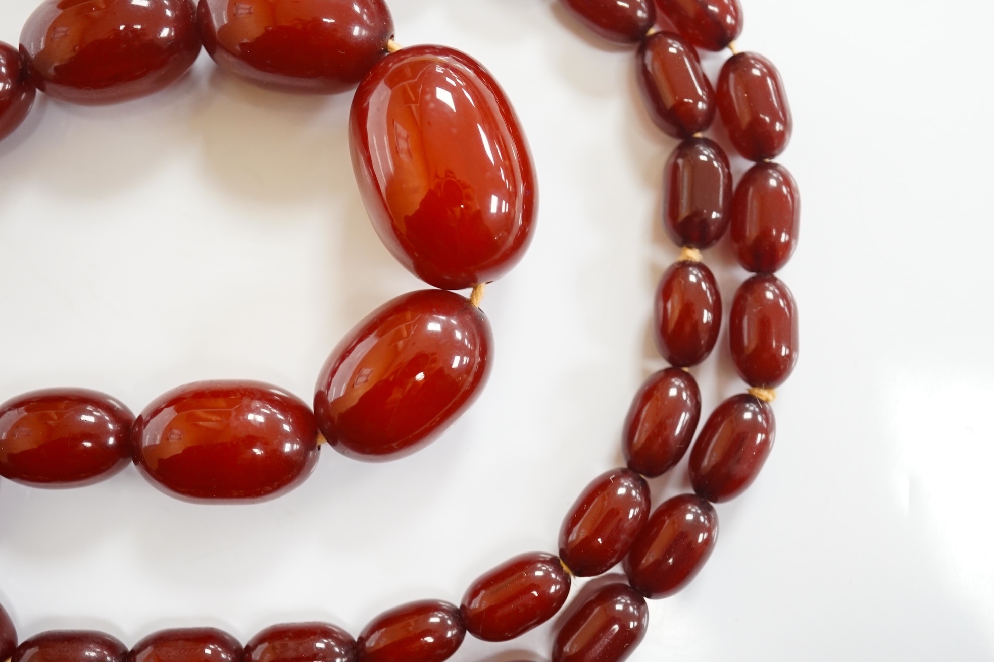 A single strand graduated simulated cherry amber oval bead necklace, 70cm, gross weight 51 grams. Condition - fair to good